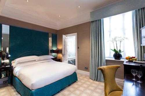 a bedroom with a bed and a desk and a window at The Capital Hotel, Apartments & Townhouse - Small Luxury Hotels of The World in London