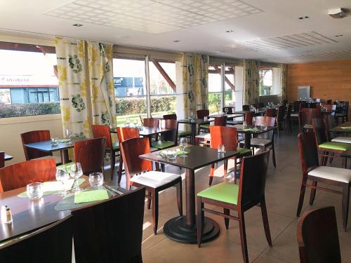 - une salle à manger avec des tables, des chaises et des fenêtres dans l'établissement Logis Hôtel-Restaurant Les Loges, à Chantepie