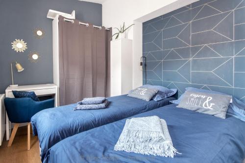 a bedroom with two beds with blue sheets at The Clock House, 3 étoiles in La Rochelle