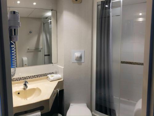 La salle de bains est pourvue d'un lavabo, de toilettes et d'un miroir. dans l'établissement Logis Hôtel-Restaurant Les Loges, à Chantepie