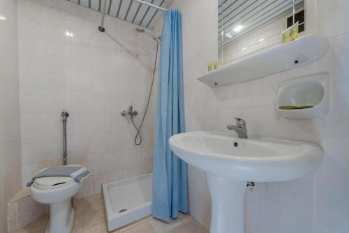 a white bathroom with a sink and a toilet at Hotel Cronulla in Kalamaki