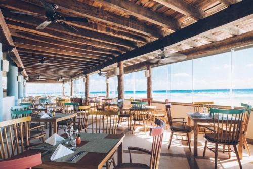 um restaurante com mesas e cadeiras e vista para o oceano em Iberostar Selection Cancun em Cancún