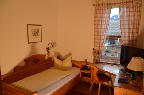 a bedroom with a bed and a desk and a window at Gästehaus Maria in Garmisch-Partenkirchen