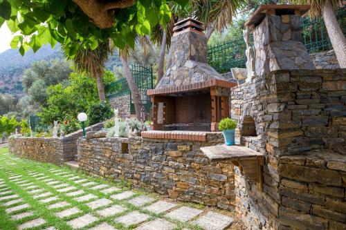 a stone wall with a stone fireplace in a yard at Villa Apelia - Family Holidays Deals in Vlikhádha