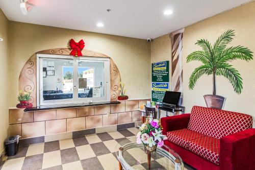 a waiting room with a red couch and a window at Scottish Inn and Suites Baytown in Baytown