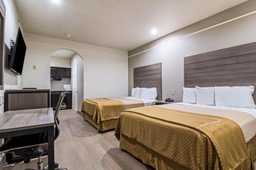 um quarto de hotel com duas camas e uma televisão de ecrã plano em Scottish Inn and Suites Baytown em Baytown