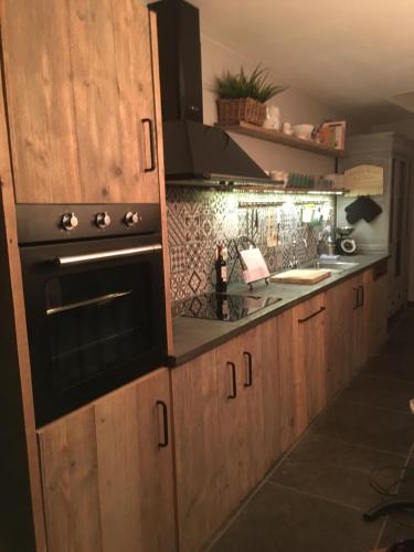 a kitchen with wooden cabinets and a black oven at La MeusÂme in Dinant
