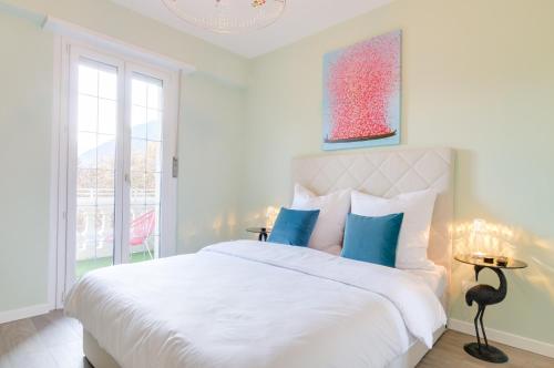 een witte slaapkamer met een groot bed met blauwe kussens bij Penthouse Jolanda Meran-o in Merano