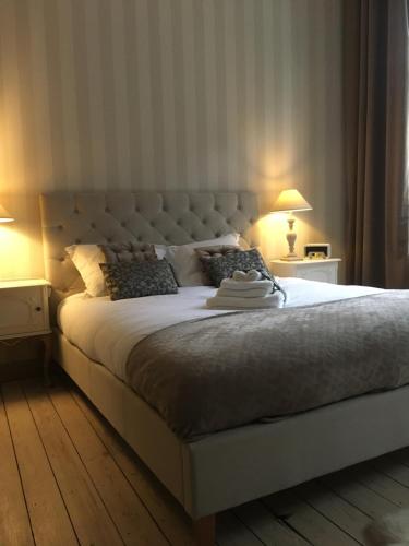 een slaapkamer met een groot wit bed met 2 lampen bij La MeusÂme in Dinant