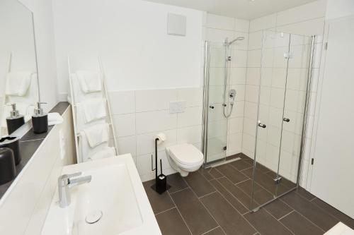 a white bathroom with a shower and a toilet at Haus Alpenherz in Oberstdorf