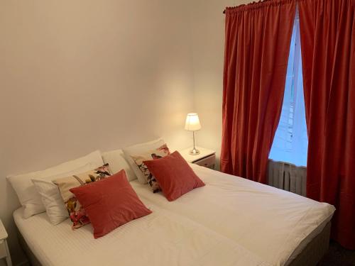 a bedroom with a white bed with red curtains and a window at Tokeryds Herrgård in Jönköping