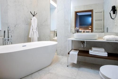 a white bathroom with a tub and a sink at Hotel M29 in Krakow