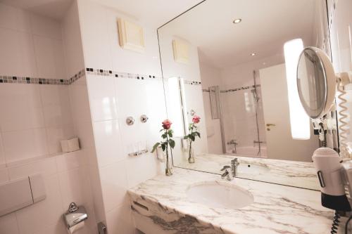 a bathroom with a sink and a mirror at Hotel Bayerischer Hof Miesbach, BW Premier Collection in Miesbach