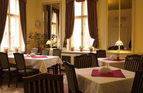 a restaurant with two tables and chairs and windows at Pensjonat Pałacyk in Łańcut