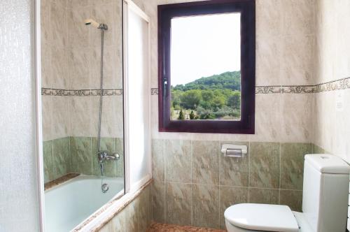 uma casa de banho com um chuveiro, um WC e uma janela. em Finca Aguilas em S'Horta