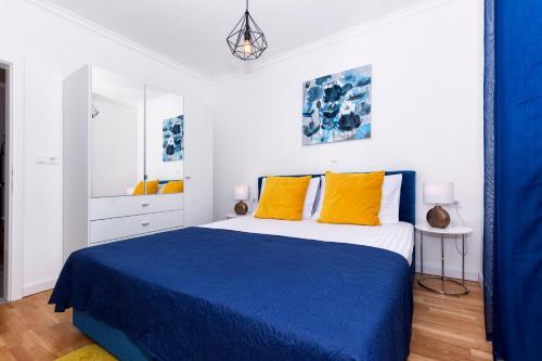 ein Schlafzimmer mit einem blauen und weißen Bett mit gelben Kissen in der Unterkunft Apartments4friends Apartment NINA in Slatine