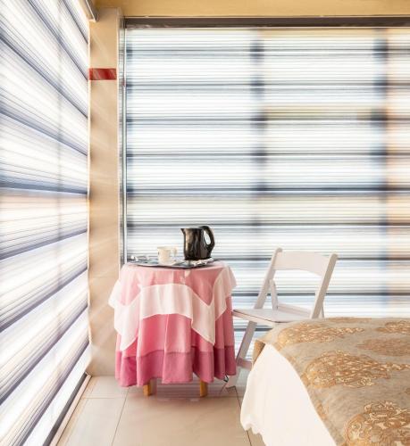 a room with a table and a window with blinds at SelaMod Village Guest House in Tshaneng