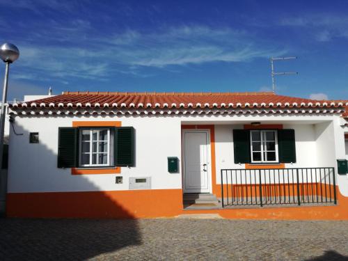 羅吉爾的住宿－Casa Pompona 1，白色和橙色的房屋,设有绿色百叶窗