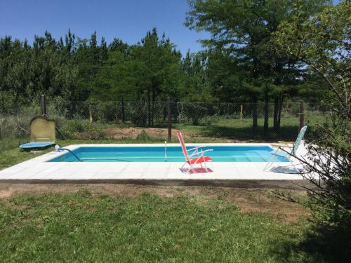 una piscina con 2 sillas en un patio en Cabañas Vientos del Sur en Villa Yacanto