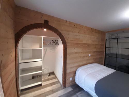 Un dormitorio con una cama y una pared de madera. en La Maison Trésallet, en La Plagne Tarentaise
