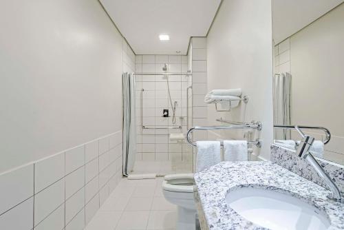 a white bathroom with a toilet and a sink at Slaviero Porto Velho in Porto Velho
