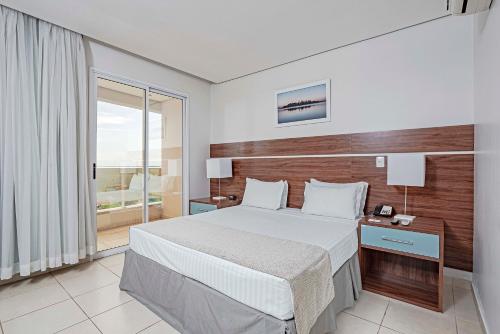 a bedroom with a large bed with a wooden headboard at Slaviero Porto Velho in Porto Velho