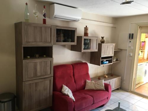 a living room with a red couch and wooden cabinets at CAVALAIRE vue MER au loin MAISONNETTE TOUT ÉQUIPÉE POUR 4 PERSONNES AVEC PISCINE CLIM WIFI VÉLOS TV BARBECUES in Cavalaire-sur-Mer