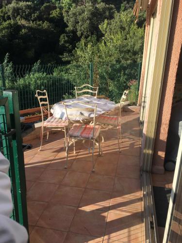 a patio with a table and chairs on a porch at CAVALAIRE vue MER au loin MAISONNETTE TOUT ÉQUIPÉE POUR 4 PERSONNES AVEC PISCINE CLIM WIFI VÉLOS TV BARBECUES in Cavalaire-sur-Mer