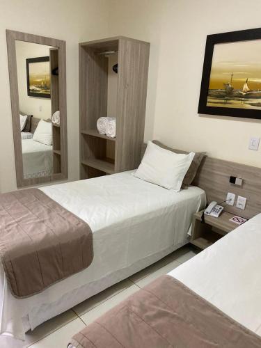 a hotel room with two beds and a mirror at Rossi Hotel in Comodoro
