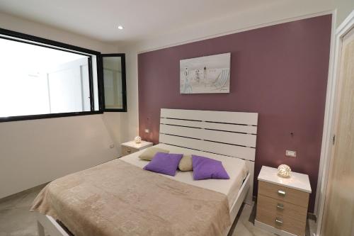 una camera da letto con un letto con cuscini viola e una finestra di Casa Giuditta Deluxe a Otranto a Otranto