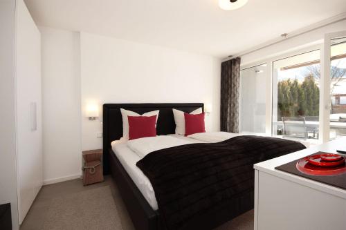Un dormitorio con una cama con almohadas rojas y una ventana en Appartement Falkenstein, en Nesselwang