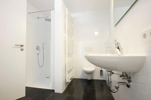 a white bathroom with a sink and a toilet at Appartement Falkenstein in Nesselwang