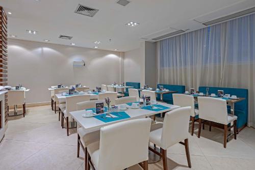 a dining room with tables and white chairs at Slaviero Porto Velho in Porto Velho