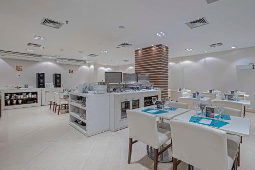 a restaurant with white tables and white chairs at Slaviero Porto Velho in Porto Velho