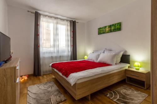 une chambre avec un grand lit recouvert d'une couverture rouge dans l'établissement Relax Apartment 3, à Sighişoara