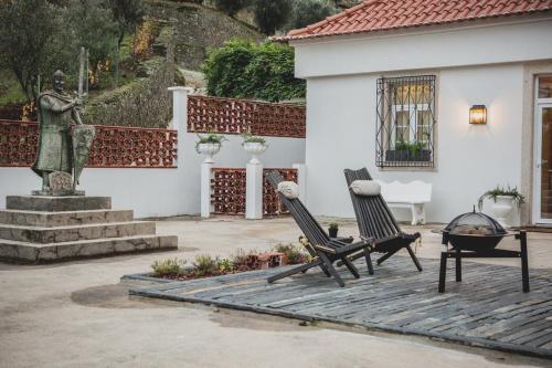 a patio with two chairs and a statue at Casal dos Capelinhos - Douro in Santa Marta de Penaguião