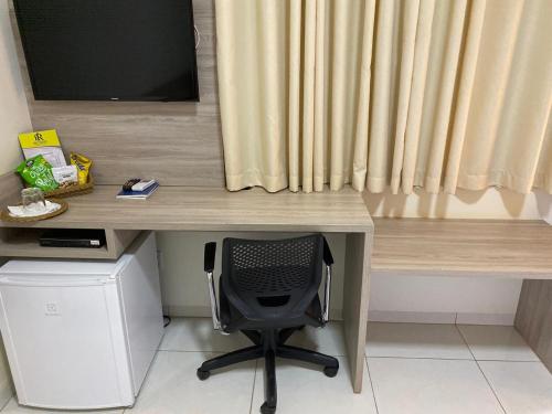 a desk with a chair in front of a television at Rossi Hotel in Comodoro