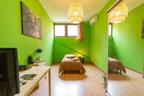 a green room with a bed and a tv at Juliette Rooms in Iesi