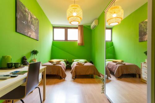 een groene kamer met 2 bedden en een spiegel bij Juliette Rooms in Iesi