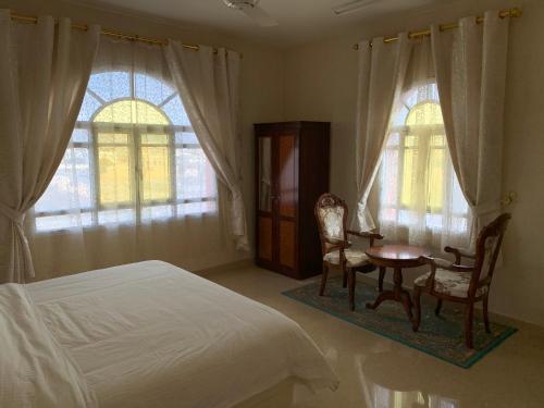 um quarto com uma cama, uma mesa e cadeiras em Al Shraija Castle , Al Jabal Al Akhdar em Al ‘Aqar