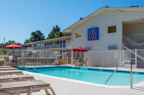 a pool in front of a hotel with chairs and umbrellas at Motel 6-Longview, TX in Longview