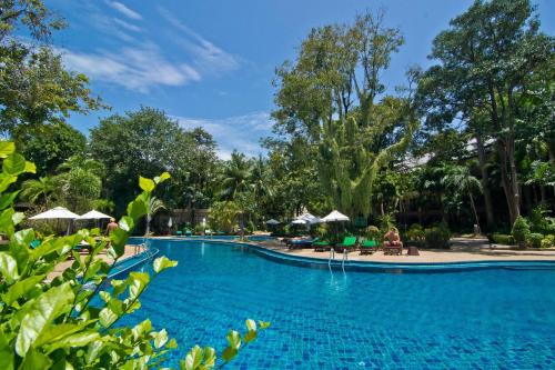 a pool at a resort with trees and umbrellas at The Green Park Resort in North Pattaya