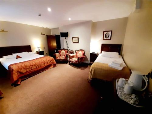 una habitación de hotel con 2 camas y una silla en JBs Bar & Guest Accommodation, en Kilkenny