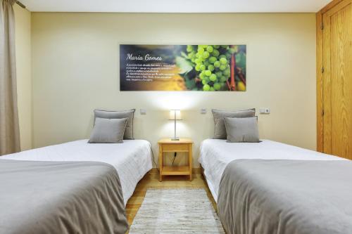 two beds in a room with a picture of grapes at Casa da Alzira in Anadia