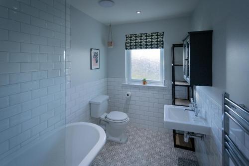 a bathroom with a tub and a toilet and a sink at The Salmon Hut in Aberlour