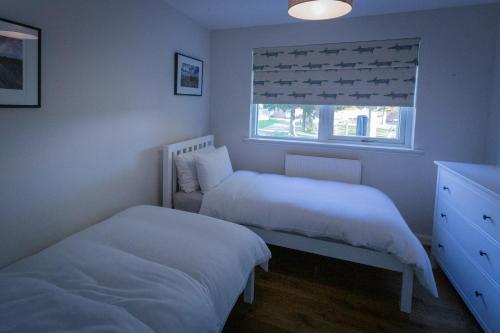 1 dormitorio con 2 camas y ventana en The Salmon Hut en Aberlour