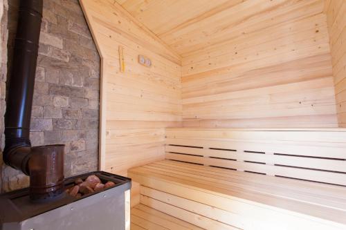 a wooden sauna with a brick wall and a stove at RELAX Guest House in Tsigov Chark