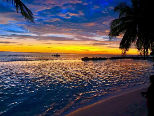 a sunset on the beach with a boat in the water at Veli Beach Inn in Mathiveri