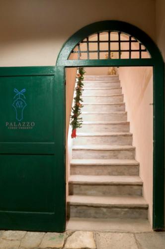 a stairway leading to a green door with stairs at Boutique Hotel Palazzo Corso Umberto in Boiano