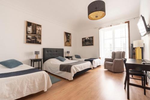 a bedroom with two beds and a desk and a chair at Burgos Guest House in Évora